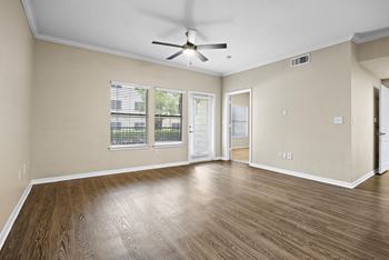 an empty living room with a ceiling fan and a window at Artisan Apartments & Shops, Austin, TX